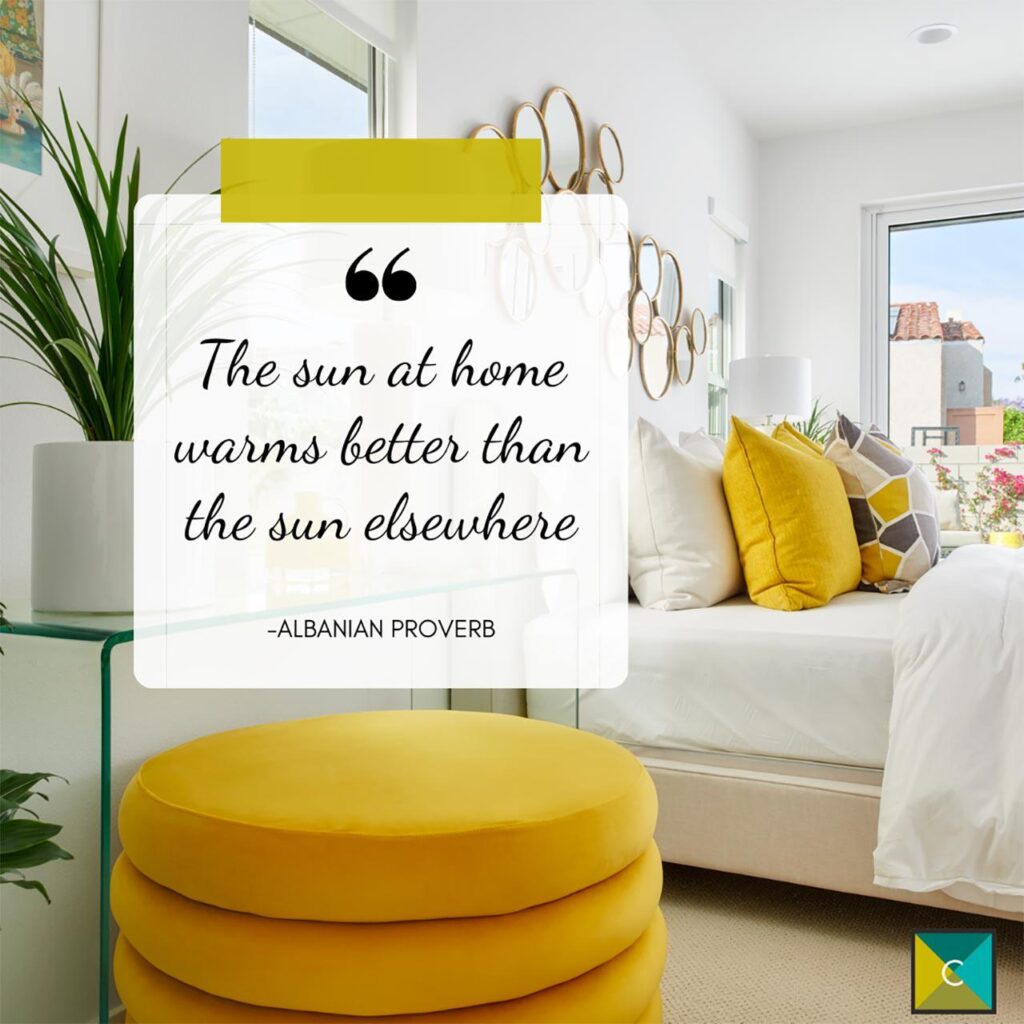 White colored home with a white couch and yellow pillows and an albanian proverb saying the sun at home warms better than the sun elsewhere in a text box