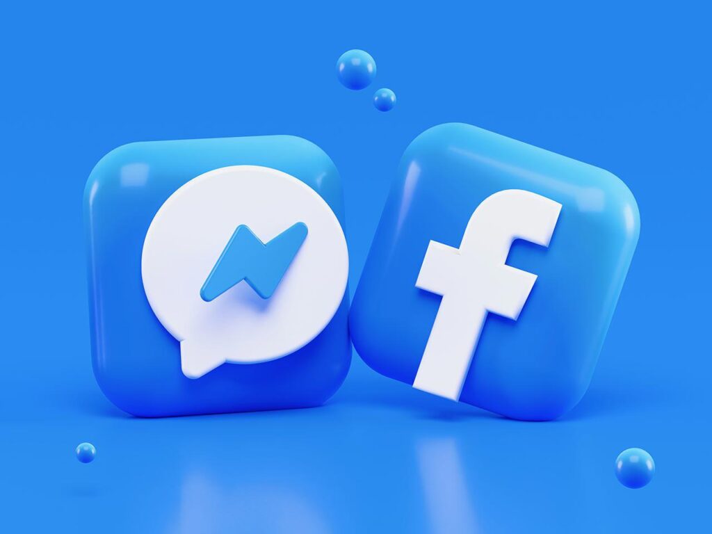 three dimensional computer generated image of the blue and white Facebook and Messenger logos in front of a blue background with small blue spheres hovering above and below the logos